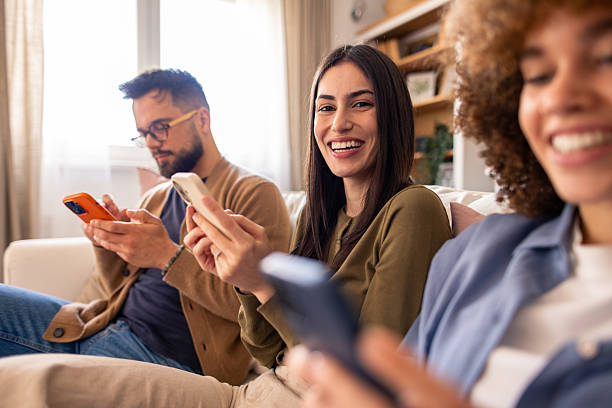istock Three Friends Smiling and Chatting on Couch While Using Smartphones in a Cozy Living Room 2212432777