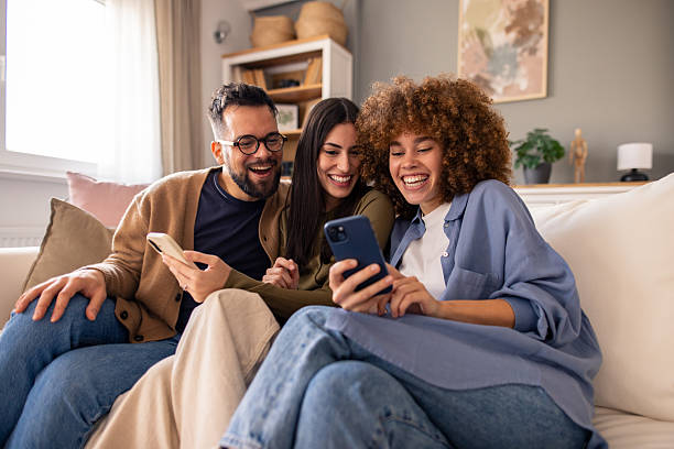 istock Three Friends Smiling and Chatting While Relaxing on a Couch with Their Phones 2212432887