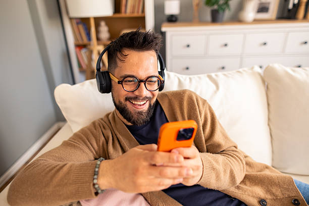 istock Young Professional With Glasses Enjoying Digital Entertainment On Smartphone While Relaxing At Home 2212432914