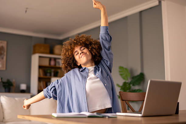 istock Curly-Haired Woman Stretching at Desk in Cozy Home Office Setting 2212433303