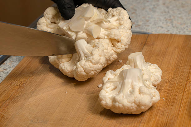 istock Chef divides a head of cauliflower into florets on a kitchen cutting board. Close-up 2212434990