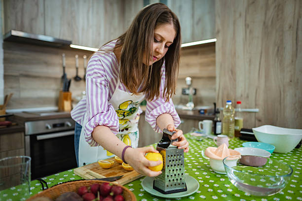 Young woman grating lemon zest in the kitchen, preparing ingredients for a recipe