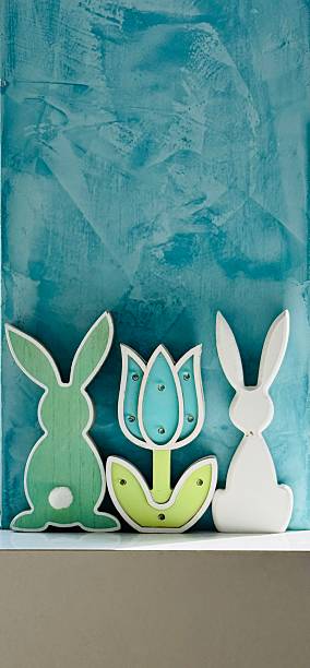 Green and white easter rabbit and a flower on a blue wall