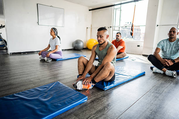 Mid adult man stretching during exercise class at gym
