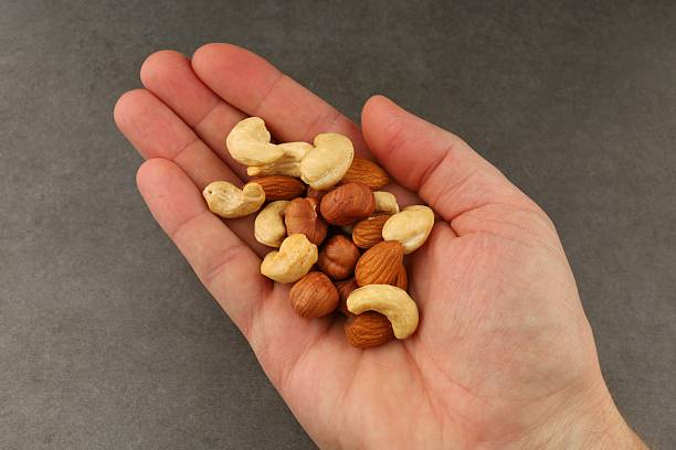 istock Handful of mixed nuts including cashews, almonds, and hazelnuts displayed against a simple background 2212444216