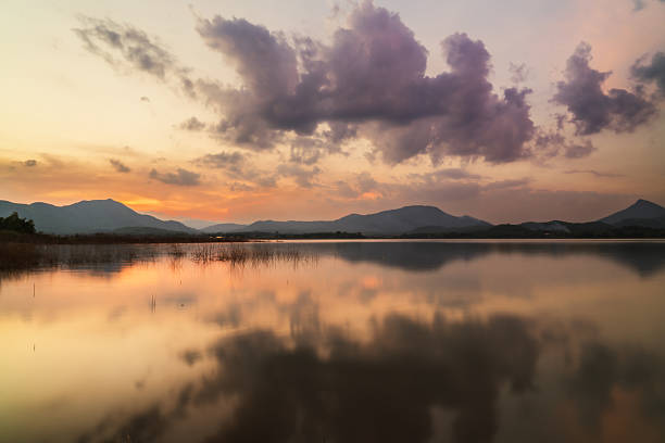 istock Sunset reflecting on calm lake with mountains and cloudy sky 2212445831