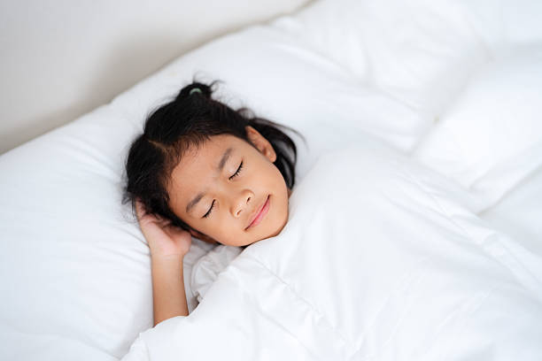 istock Little girl sleeping peacefully in white bedding 2212446440