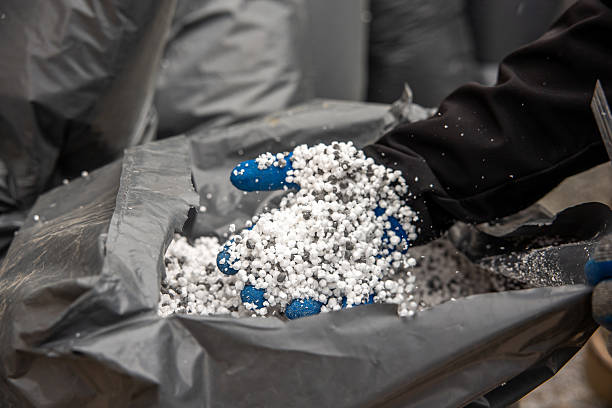 istock Gloved Hand Holding White Granular Material from Large Gray Bag 2212449015