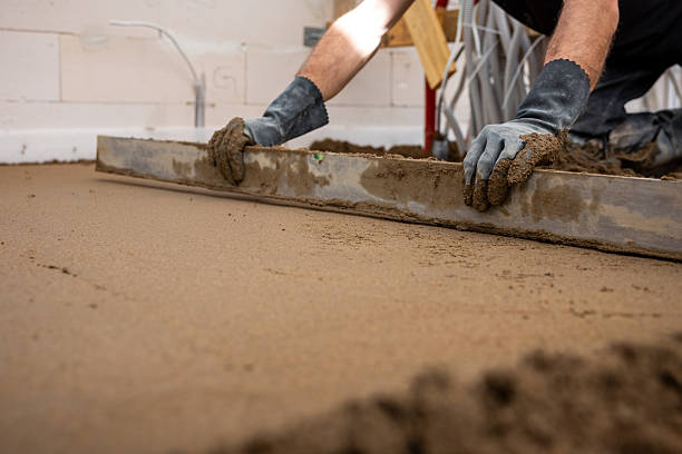istock Worker Levels Wet Concrete for Underfloor Heating Installation Indoors 2212451408