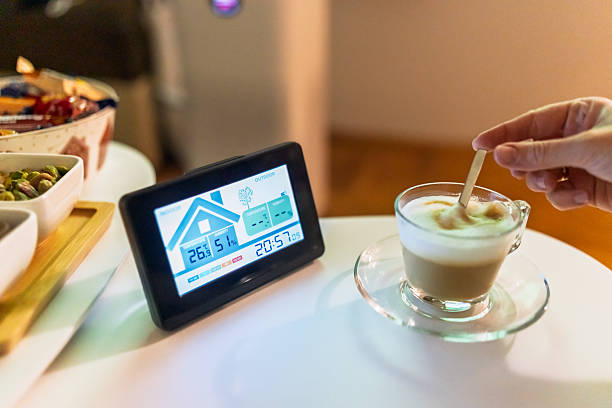 A smart indoor climate monitor displayed on a white table next to a cup of coffee and snacks, creating a cozy and modern home atmosphere.