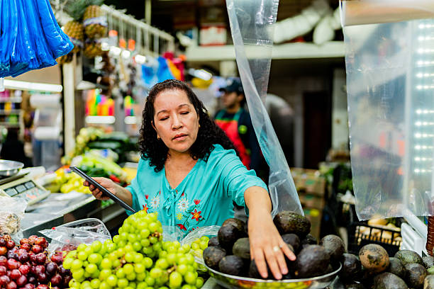 Mature saleswoman using digital tablet at market