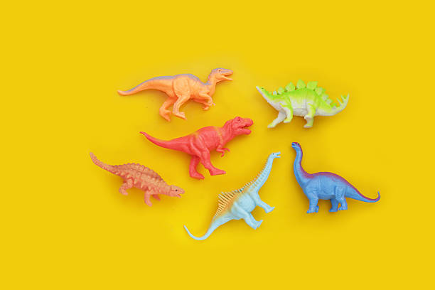 istock Plastic dinosaur toys on yellow background 2212456987