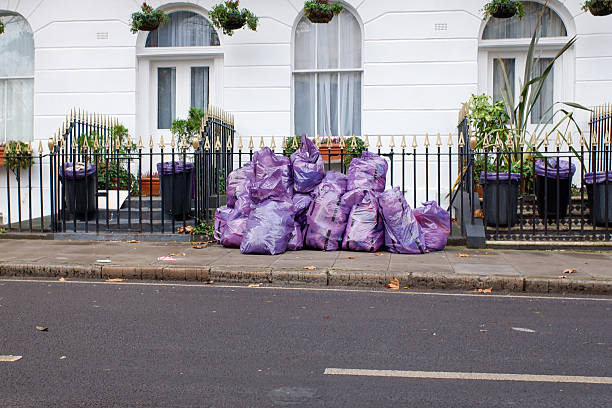 Rubbish collection day in Old Bond Street in the West End of London. Each store places their rubbish on the road side of the pavement where it is collected by the collection truck. Old Bond Street contains many famous luxury stores but, whoever they are, they still produce bags of rubbish!