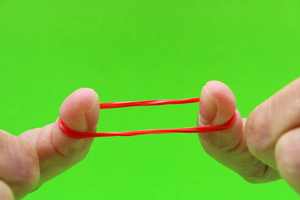 istock Two fingers extending a red rubber band 2212458744