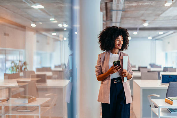 istock Smiling businesswoman holding smartphone and documents in modern office 2212460557