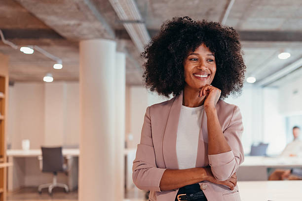 Smiling businesswoman looking away while standing in modern office