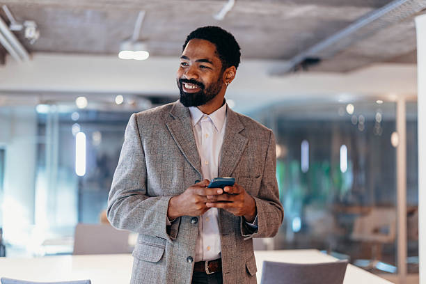 istock Smiling businessman using smartphone in modern office 2212460743