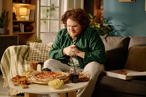 istock Smiling Man Enjoying Pizza on Sofa in Living Room 2212460856