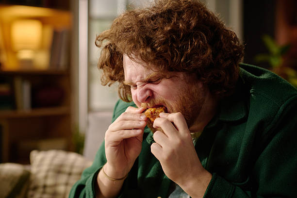 istock Man Enjoying Eating Crispy Fried Chicken Indoors 2212461924