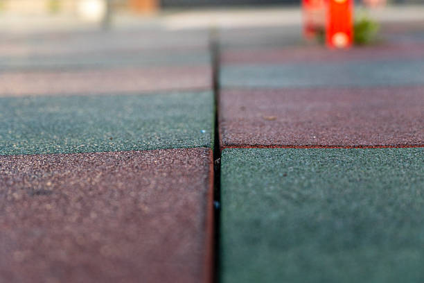 istock Playground flooring features alternating red and green rubber tiles with a focus on texture and color, creating a vibrant environment for kids 2212462297