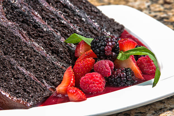 istock Chocolate cake decorated with chocolate chips, accompanied with red berry sauce and served with red berries 2212467662