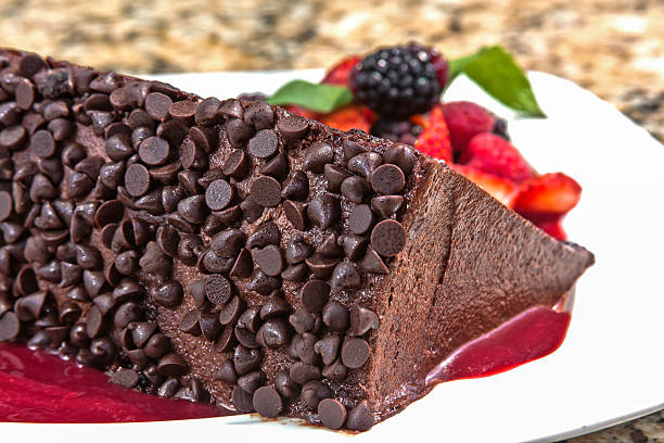 istock Chocolate cake decorated with chocolate chips, accompanied with red berry sauce and served with red berries 2212467663