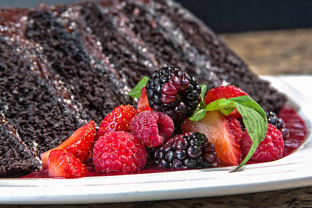istock Chocolate cake decorated with chocolate chips, accompanied with red berry sauce and served with red berries 2212467813