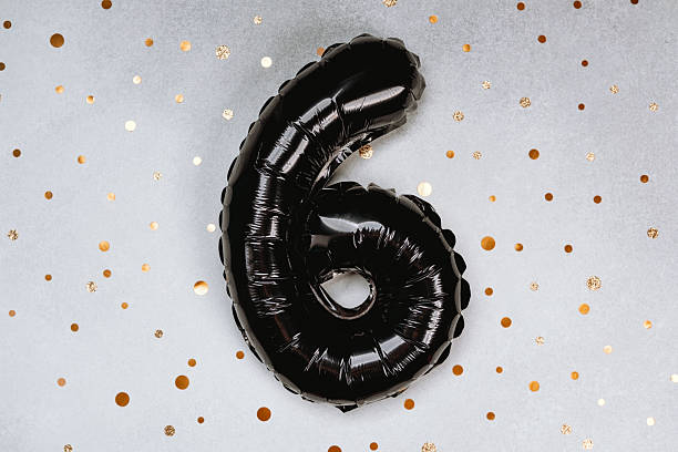 istock Black balloon number six on a sparkly gold dotted background for celebration 2212474975
