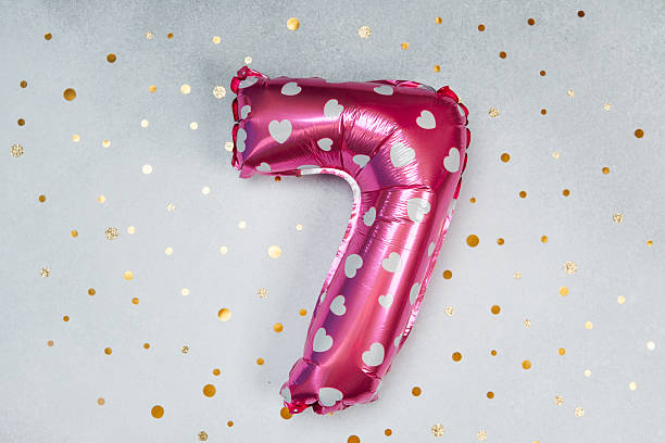 istock Celebration with a shiny pink number seven balloon on a glittery background 2212474983