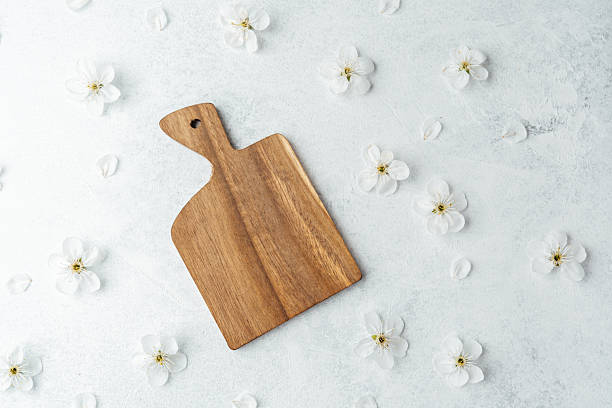 istock Wooden serving board on a textured surface with delicate white flowers 2212475013