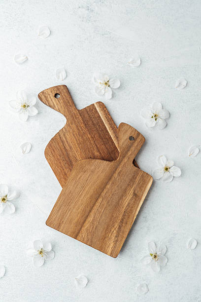 istock Wooden cutting boards arranged on white surface with flower petals 2212475018
