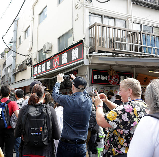 Chuo Ward, Japan - April 7, 2025: International visitors try to enter crowded Tsukiji Outer Market from Namiyoke-dori Street. Spring mid-morning in the Tokyo Metropolis.