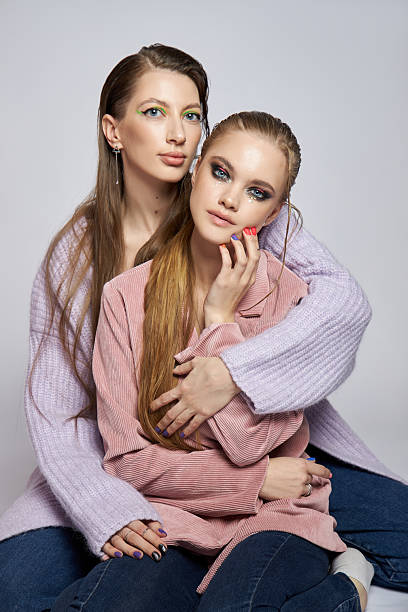 istock Two friends share an affectionate moment while posing in a studio. They display vibrant makeup styles against a neutral background, highlighting their connection and individual personalities 2212484034