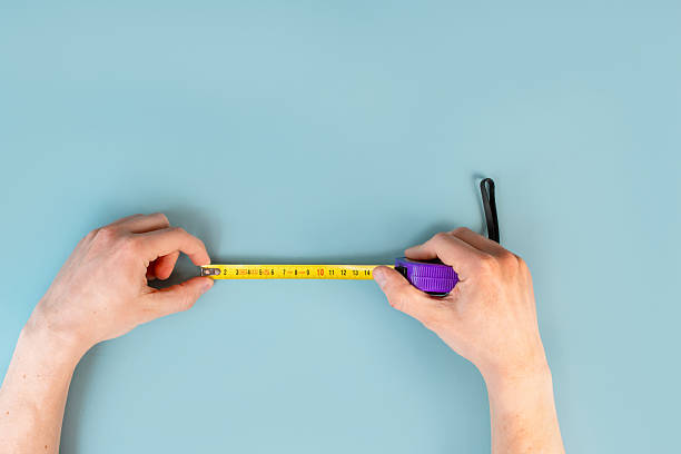 istock A man's hands hold a construction tape measure on a blue table background. The concept of repair. Close up, point of view shot. 2212504251