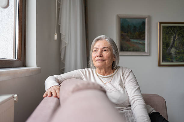 istock Senior Woman Looking Outside The Window 2212508551