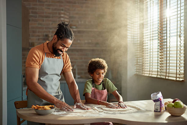 istock Happy black father and son kneading dough in the kitchen. 2212509528