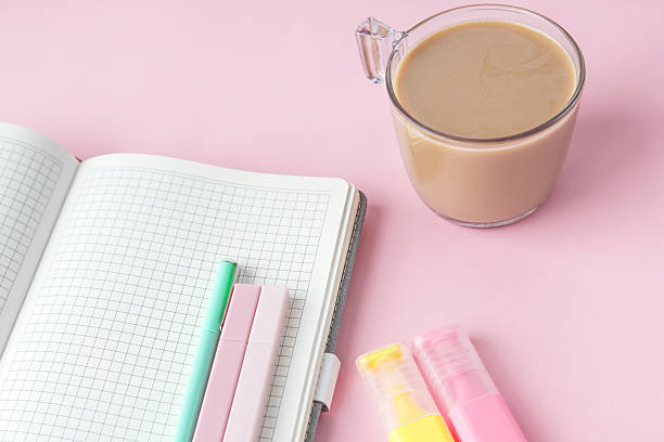 istock An open grid notebook with pastel pens, highlighters, and a cup of coffee placed on a pink background. The workspace setting reflects focus and creativity. Concept of studying and productivity 2212509882