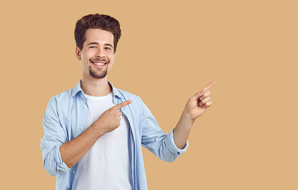 istock Happy, handsome groomed young man with neatly shaved beard and mustache smiles and points with both hands to the side at empty isolated copy space. 2212510687