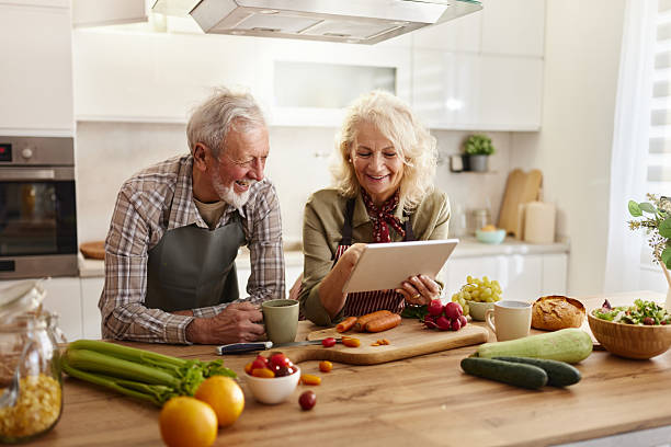 istock Happy senior couple using touchpad while preparing food in the kitchen. 2212511085