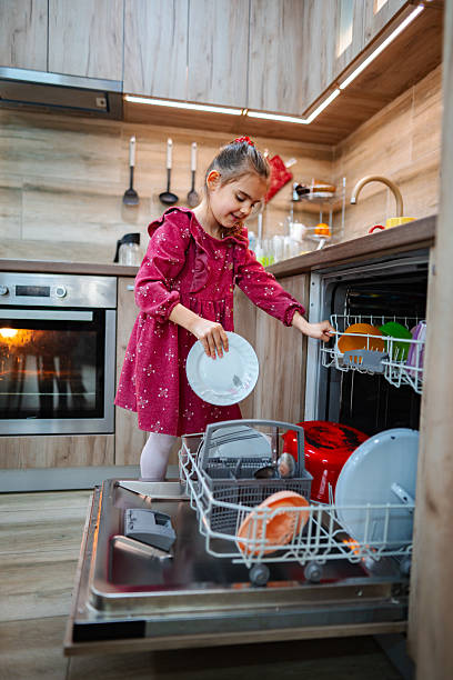 istock Little girl loading the dishwasher in a modern kitchen 2212513005
