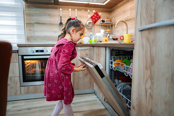 istock Little girl opening dishwasher in kitchen 2212513034