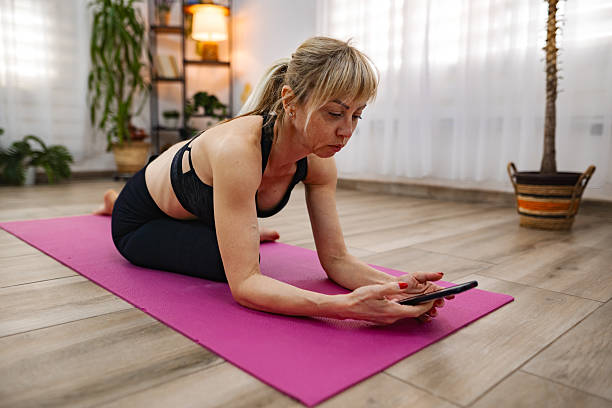 istock Woman doing yoga and using smartphone at home 2212513376
