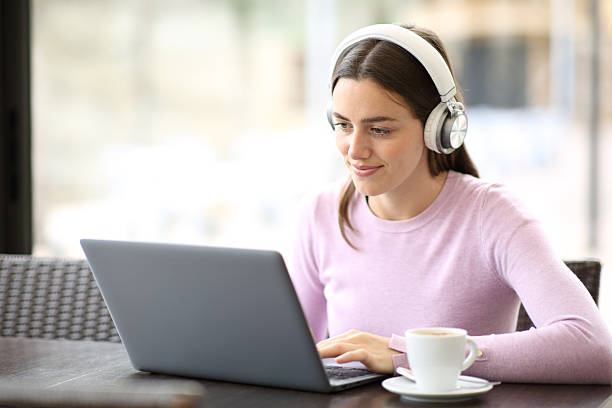 istock Woman wearing headphone using laptop in a restaurant 2212515280