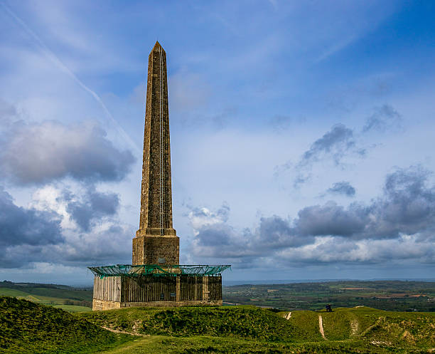 istock Tall stone obelisk on a grassy hill under a cloudy blue sky in a rural landscape 2212516752