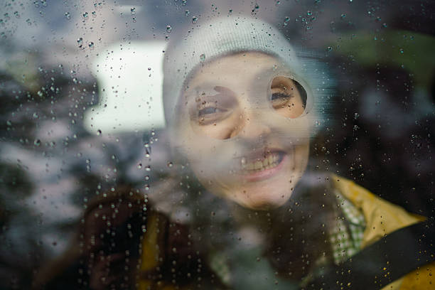 Young woman having fun drawing on a window during rainy day in a car