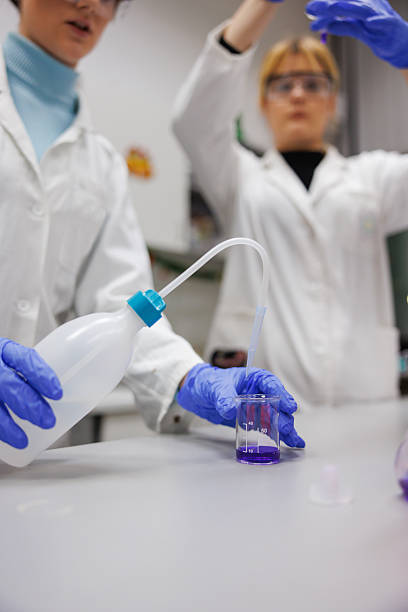 istock Female students practicing in lab with chemicals, wearing lab coats, gloves and protective eyewea 2212517992