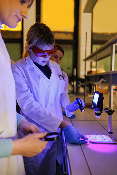 istock Group of university students wearing lab coats using ultraviolet light in research practice 2212518292