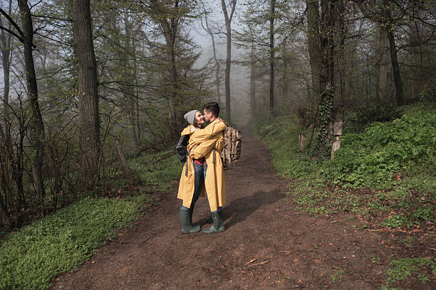 Full length of happy young couple whit backpacks standing and embracing in the forest