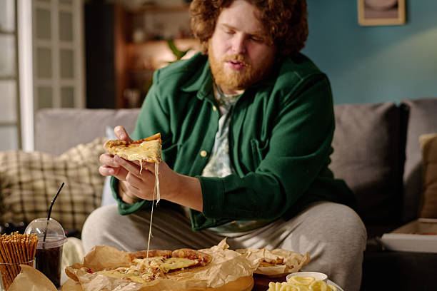 Man Enjoying Hot Melted Cheese Pizza at Home