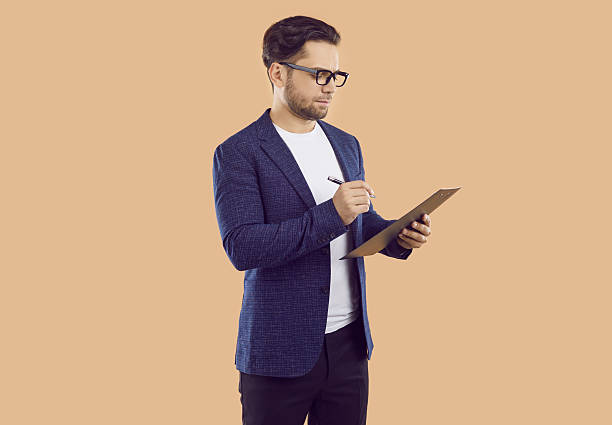Business man or sales manager in suit and glasses writing something on clipboard stock photo